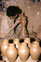 Image du Maroc Professionnelle de  Comme Safi est le chef-lieu de la poterie céramique marocaine, c’est à l’intérieur de son atelier que l’artisan tourneur travaille l'argile brute puis le transforme ainsi dans sa forme, souvent il s'agit d'objets de forme essentielle destinés à l'usage domestique. Quand l’objet est façonné selon le besoin une petit lame est utilisé pour donner à l'objet un aspect lisse. Souvent les artisans ont recours à leur dextérité afin de fignoler la décoration à Safi Vendredi 29 Août 1997.(Photo / Abdeljalil Bounhar)